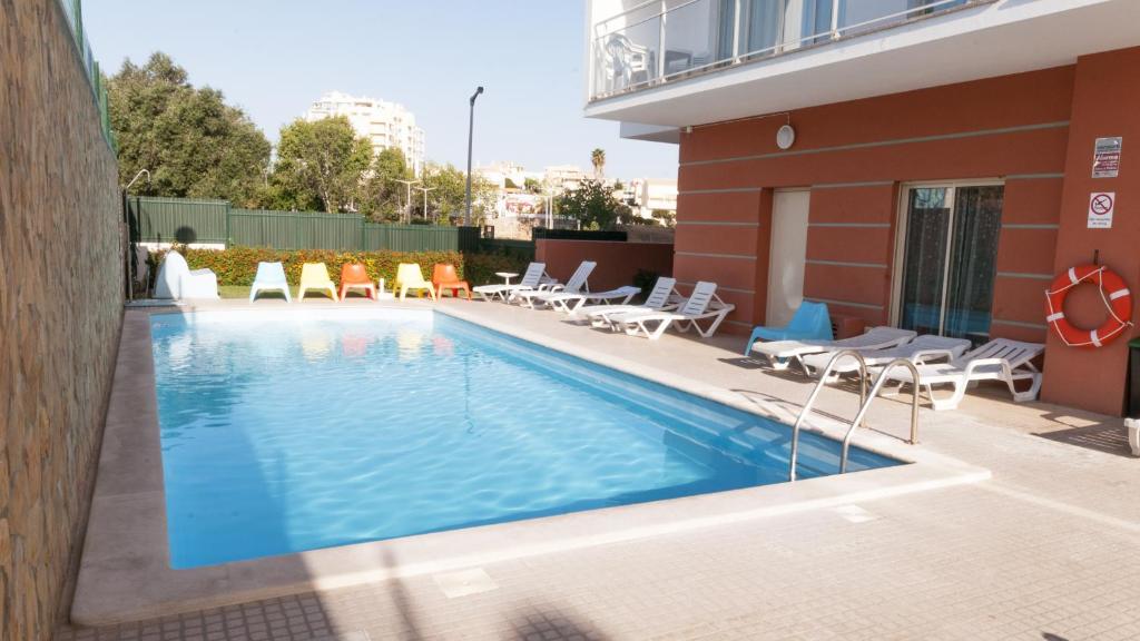 una piscina con sillas y un edificio en Studio 17 by Atlantichotels - AL, en Portimão