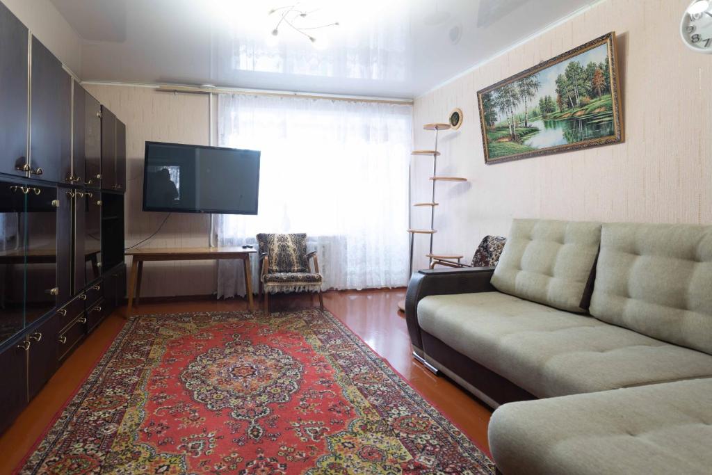 sala de estar con sofá y TV de pantalla plana en Самара, en Petropavlovsk
