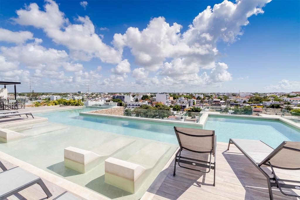 einen Pool mit Stühlen und Stadtblick in der Unterkunft Estudio VERANTO in Playa del Carmen