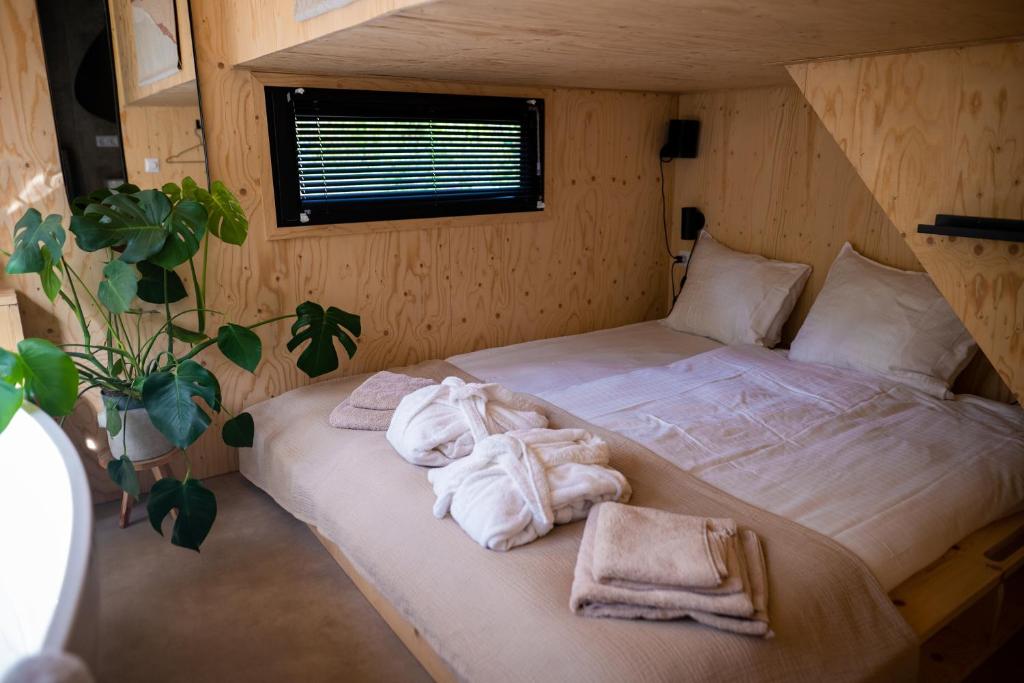 1 dormitorio con 1 cama con toallas en Vague Luxurious Tiny House Luxe Wellness, Spa Bad,Beamer, Veluwe, en Nunspeet