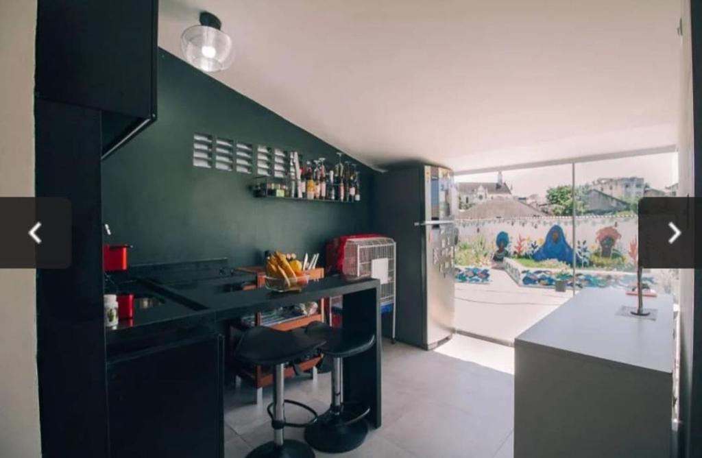 une cuisine avec un comptoir noir et un mur vert dans l'établissement Tamboleiro's Hotel Residence, à Salvador