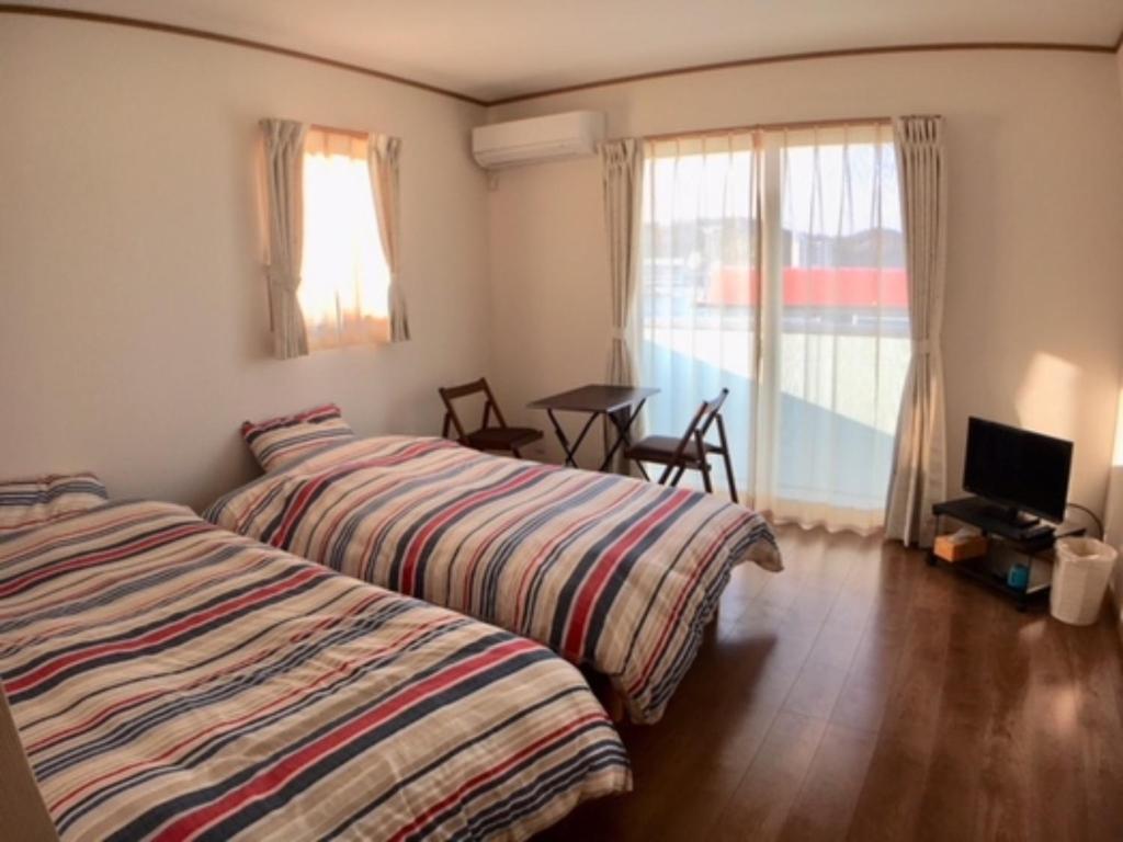 1 dormitorio con 2 camas, mesa y ventana en Seaside Hostel Light House - Vacation STAY 82336v en Onomichi
