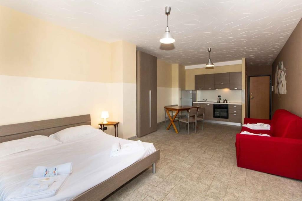 um quarto com uma cama branca e um sofá vermelho em CasaJaky em Sauze d'Oulx