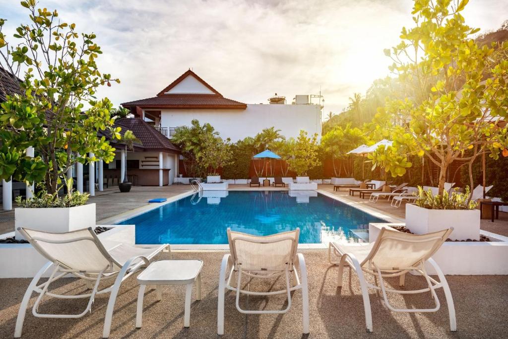 einen Pool in einem Hotel mit Stühlen und Tischen in der Unterkunft The Sands 2 bedroom apartment Naiharn in Nai Harn Beach