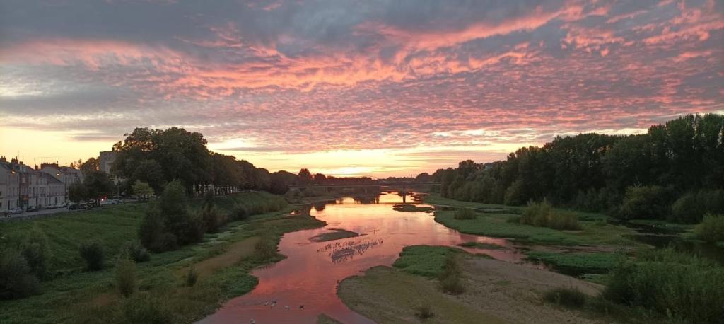 a view of a river at sunset at Cosy Loire, T2 neuf, front de Loire ,vue cathédrale,5min à pied centre ville et parking privé in Orléans