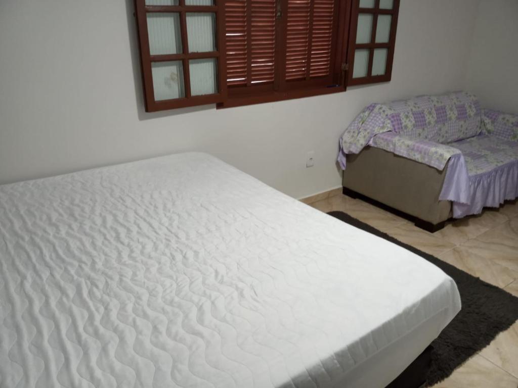 um quarto com uma cama branca e uma saia-cama em housecabofrio em Cabo Frio