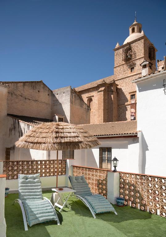a group of chairs and an umbrella on a patio at Balcón a la Sierra - Terraza y Hermosas Vistas in Illora
