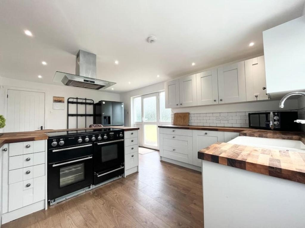 a kitchen with white cabinets and a black stove top oven at Bright Bungalow with 3 bedrooms and Garden in Porthlevan in Porthleven