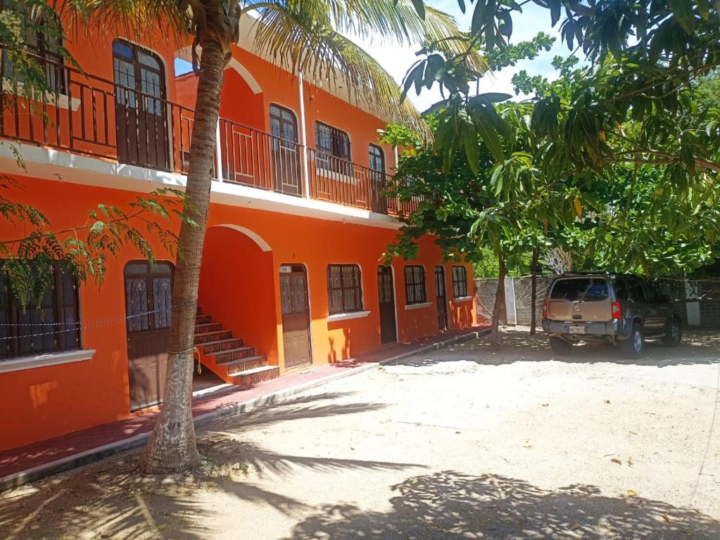 Un bâtiment orange avec une voiture garée devant. dans l'établissement cuartos en renta El portón azul, à Ixtepec