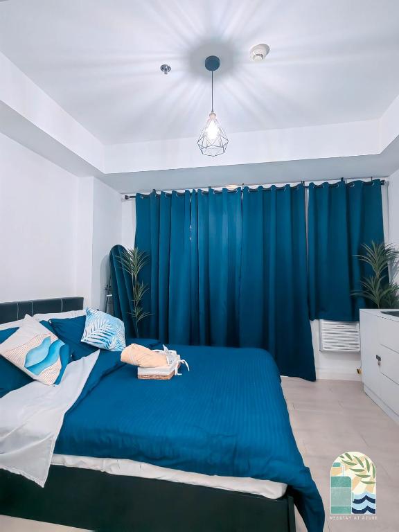 Schlafzimmer mit blauem Bett und blauen Vorhängen in der Unterkunft Azure Blue Cozy Unit with PS4 & Netflix in Manila
