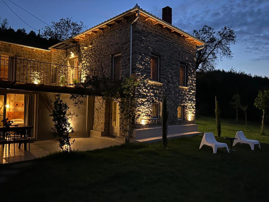 a stone house with two white chairs in front of it at Εn Kanaliois in Kanália