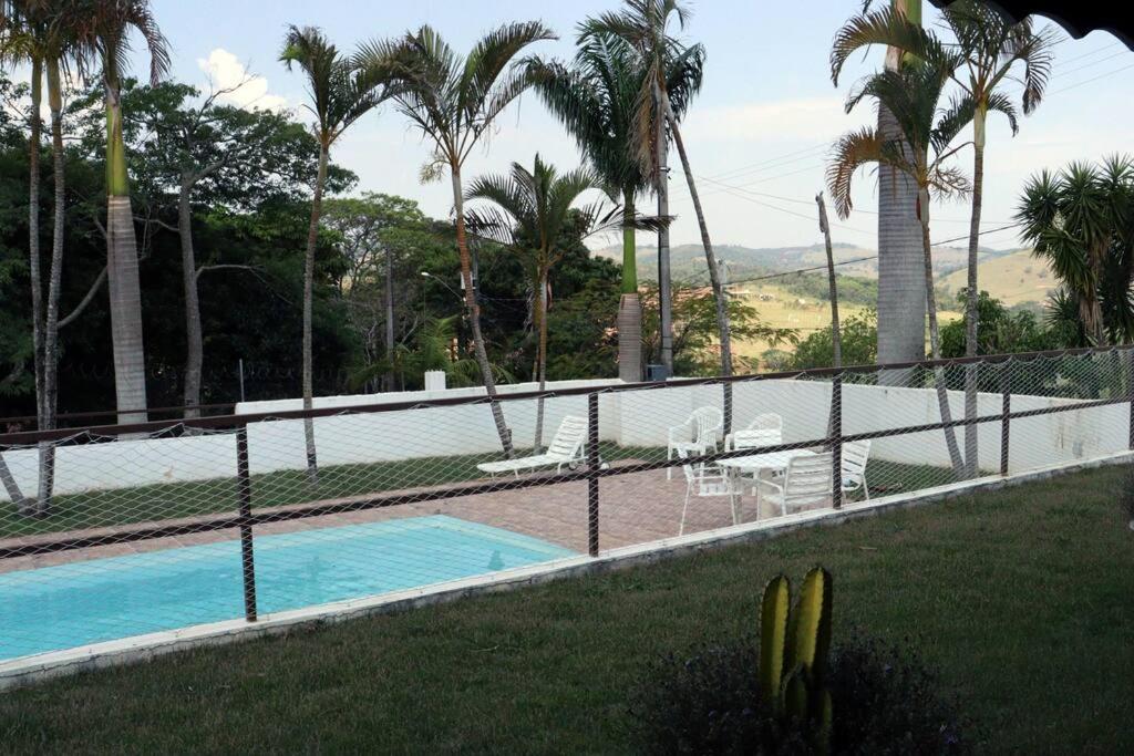 una valla junto a una piscina con palmeras en Vila verde, en Piracaia