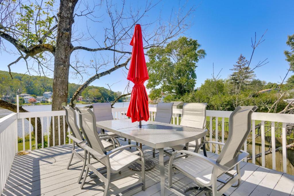 una mesa con sillas y una sombrilla roja en una terraza en Waterfront Lake Hopatcong Vacation Rental with Dock, 