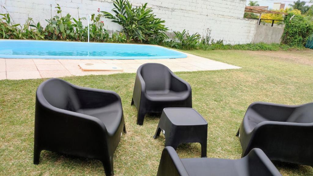4 chaises noires et une table à côté de la piscine dans l'établissement El Escaparate, à La Chacarita