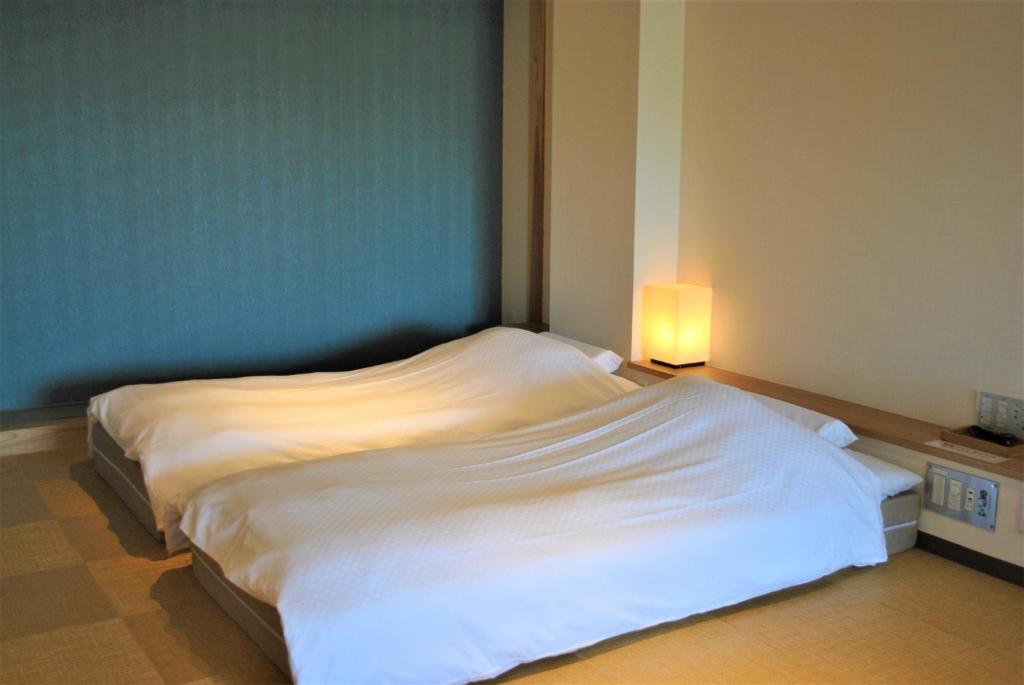 a bedroom with a white bed with a light on it at Kajitsu no mori - Vacation STAY 53781v in Ichinoseki