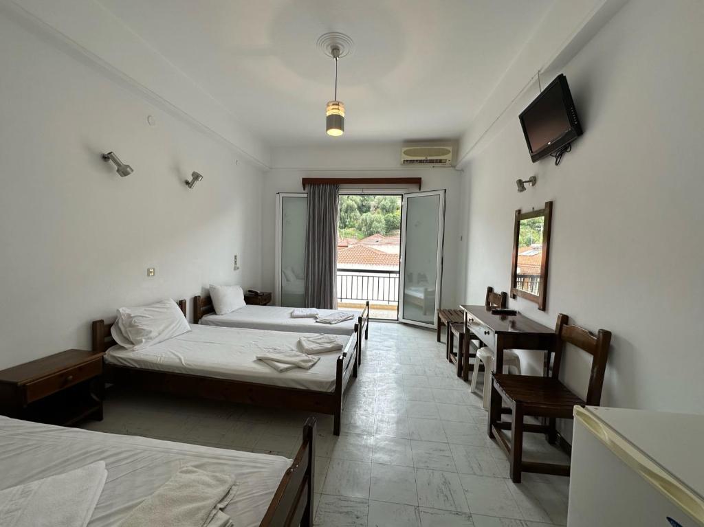 Habitación con 3 camas, escritorio y TV. en Hotel Galini, en Parga