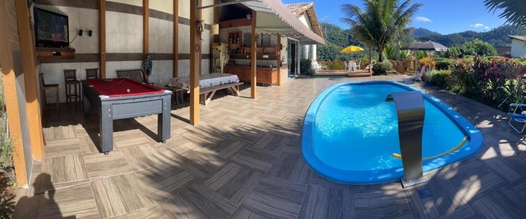 a backyard with a pool and a ping pong table at Casa nas montanhas com piscina e vista panorâmica in Domingos Martins