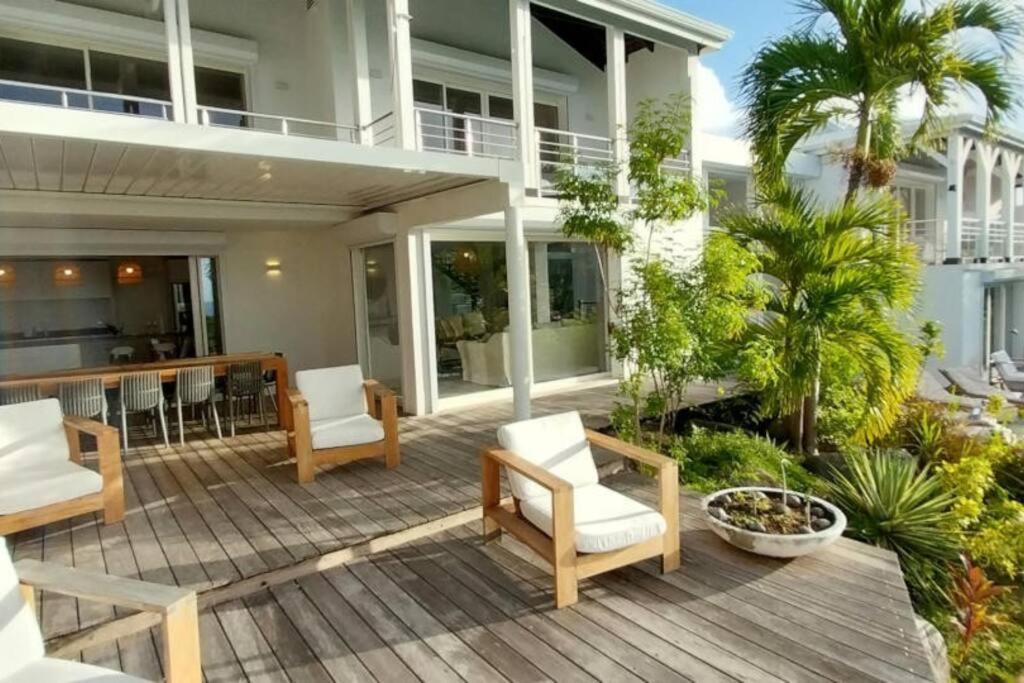 a patio with white chairs and a house at 7 bedrooms Villa, Nestled in the heights of Anse Marcel, one of the most discreet bays of the island. in Saint Martin