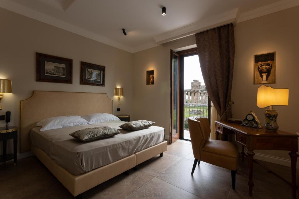 a bedroom with a bed and a desk and a window at Domus Clelia Paestum Antica Luxury rooms in Paestum