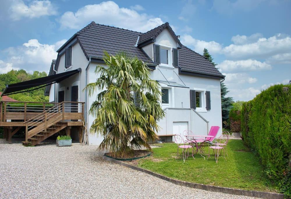 uma casa branca com duas cadeiras e uma palmeira em Charme et détente avec piscine proche de Mulhouse em Flaxlanden