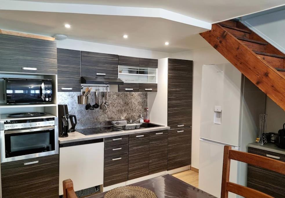 a kitchen with wooden cabinets and a stove top oven at Maison au cœur du Revermont in Ménétru-le-Vignoble