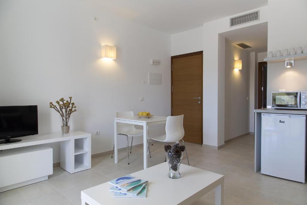 a living room with a table and a kitchen at Apartamentos Proa - Emar Hotels Only Adults in Es Pujols