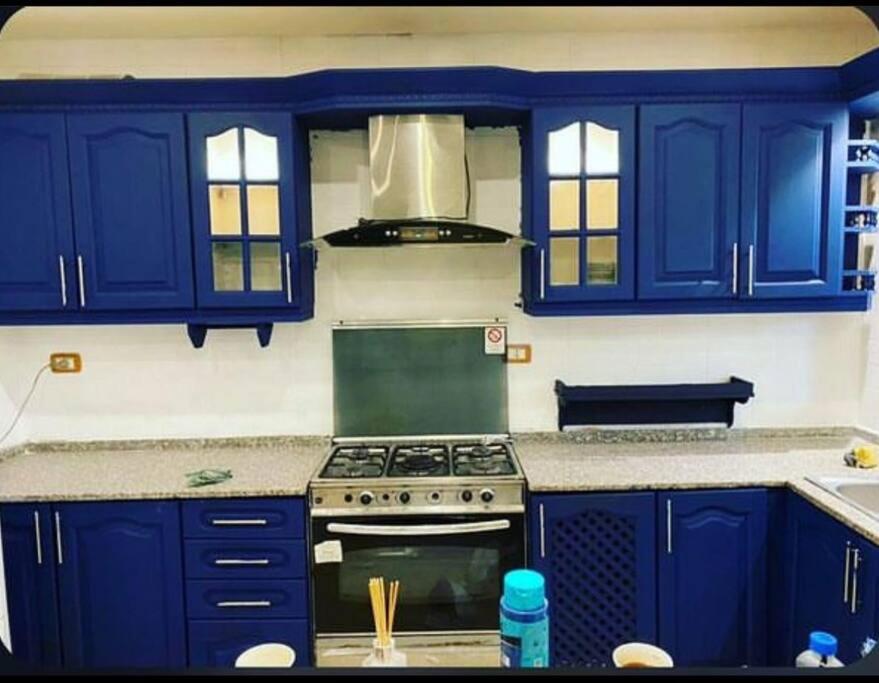 Cozy Farm في عمّان: مطبخ مع دواليب زرقاء وموقد