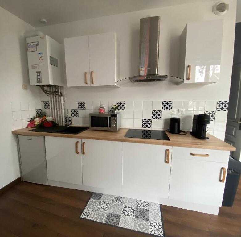 a kitchen with white cabinets and a microwave at Grand studio avec spa, cosy et rénové au cœur de Soissons in Soissons