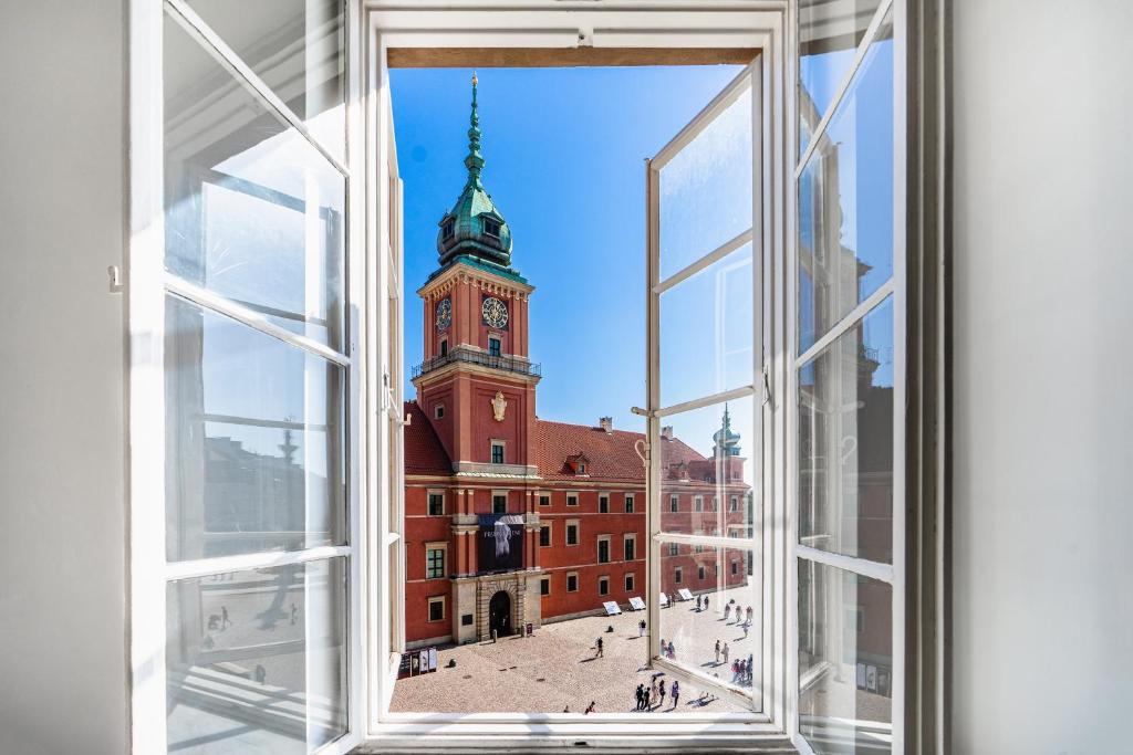 una finestra aperta con vista su un edificio con torre dell'orologio di Warsaw Castle Apartments - Prime Location, Historic City Center, Castle View, Fast Internet - by Rentujemy a Varsavia