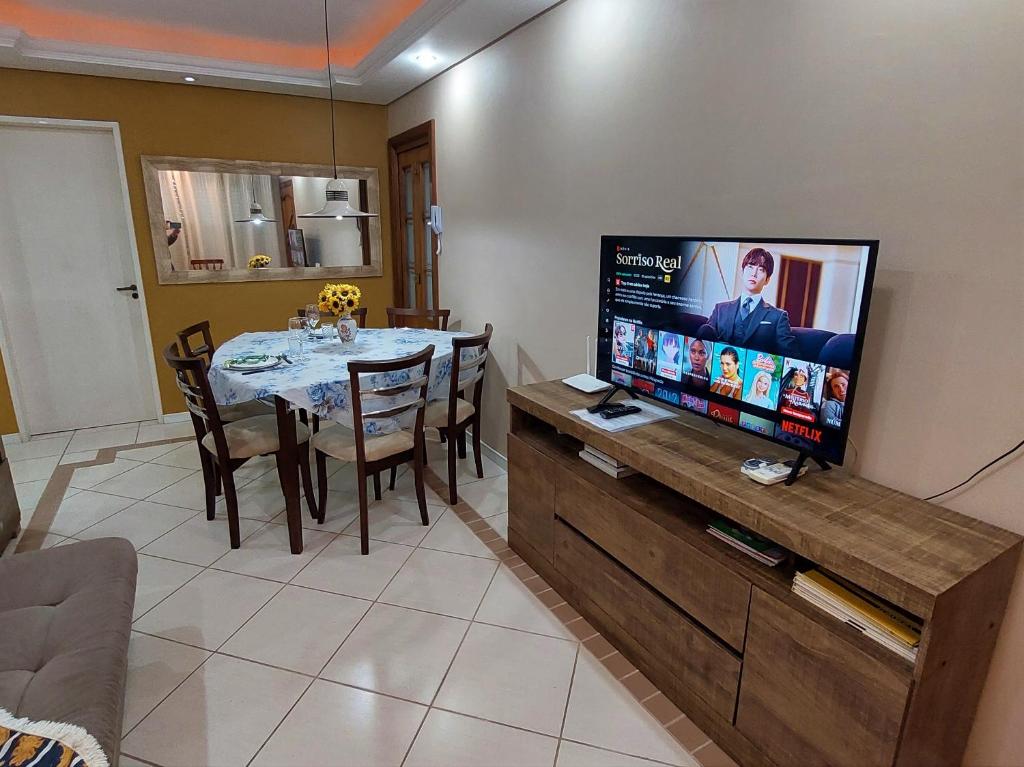 uma sala de estar com uma mesa e uma televisão de ecrã plano em Apto Familiar Completo, 2 quartos em Porto Alegre