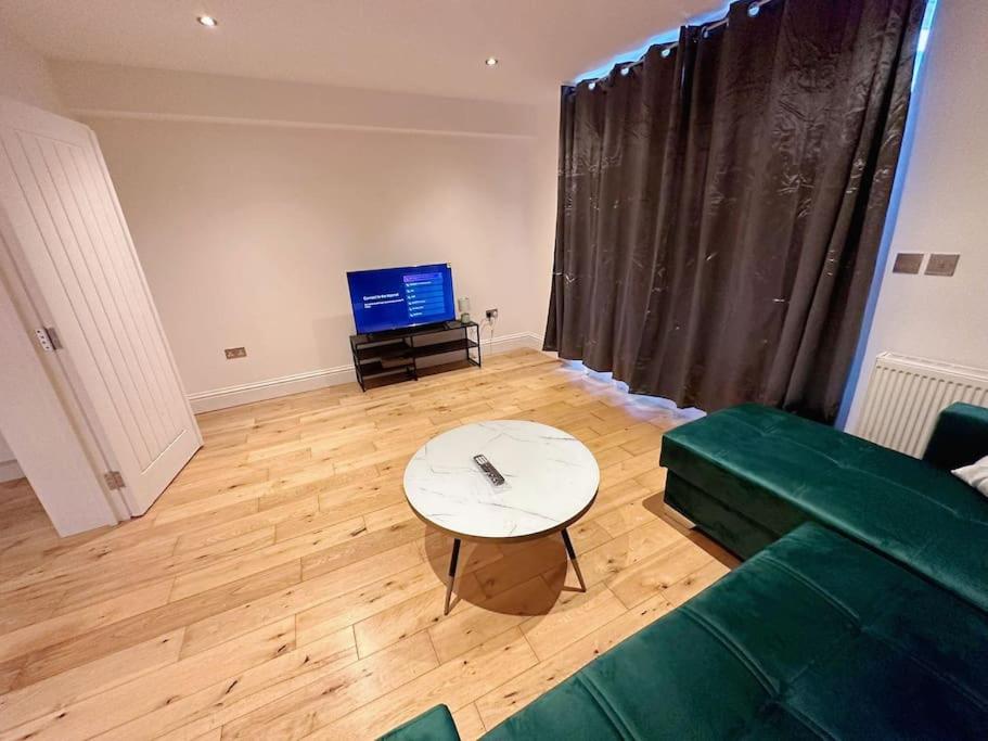 uma sala de estar com um sofá verde e uma mesa em 1 Bed Room Flat Near Central em Londres