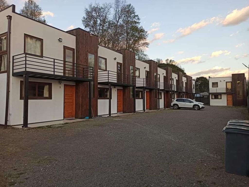 a row of buildings with a car parked in a parking lot at Cabañas L Calafquen in Licán Ray