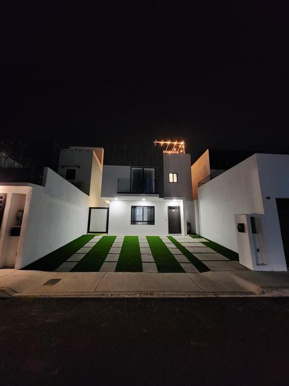 a white building with a green courtyard at night at New panoramic Ocean view relaxing home Rosarito BC in Harry Manzo