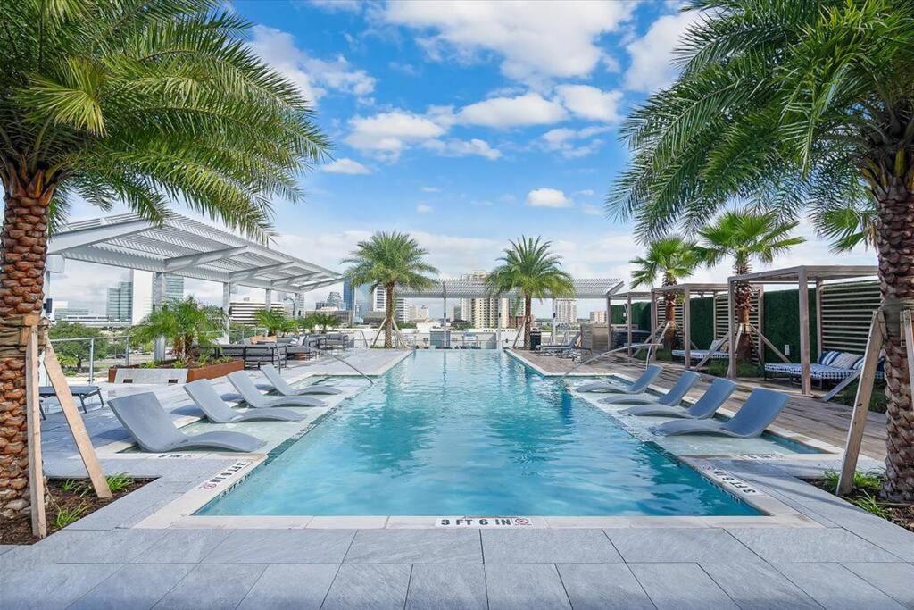a swimming pool with lounge chairs and palm trees at New Jax City Rooftop Pool in Jacksonville