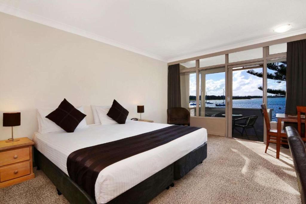 1 dormitorio con 1 cama y vistas al océano en Comfort Resort Waters Edge en Port Macquarie