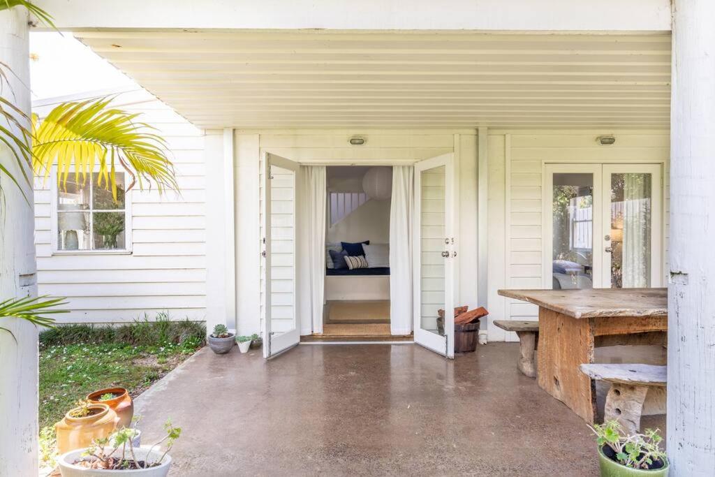 un porche d'une maison blanche avec une table en bois dans l'établissement Surfers Palace Torquay 1 min walk to beach, à Torquay