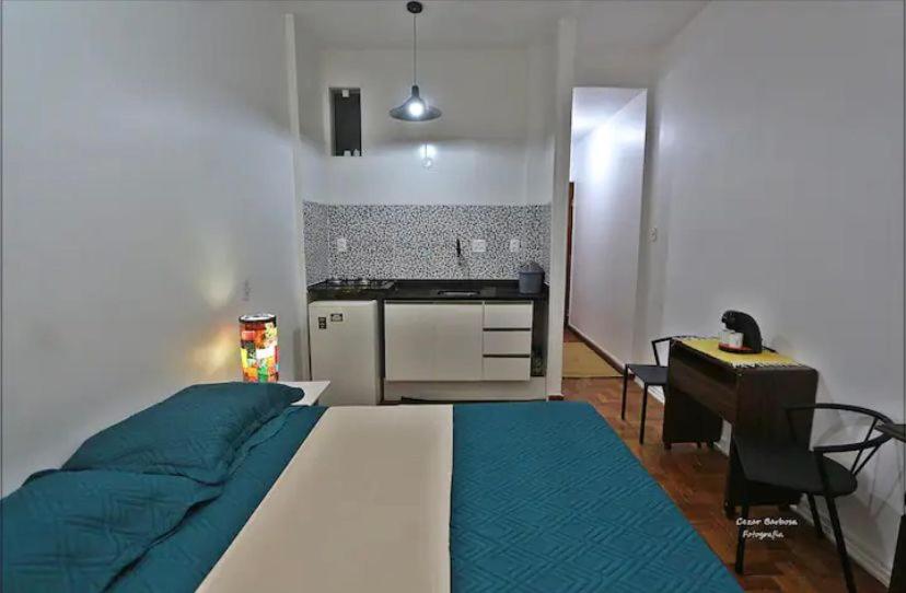 een slaapkamer met een bed, een bureau en een keuken bij Cantinho Carioca Apto em Copacabana in Rio de Janeiro