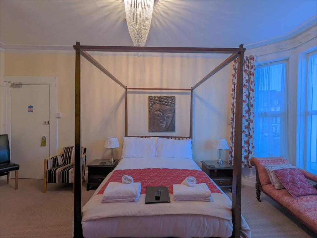 a bedroom with a canopy bed and a couch at The Senarth in Llandudno