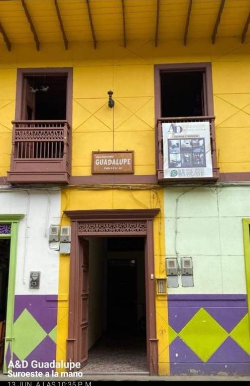 um edifício amarelo e roxo com uma porta e varanda em GUADALUPE 102 em El Charquito