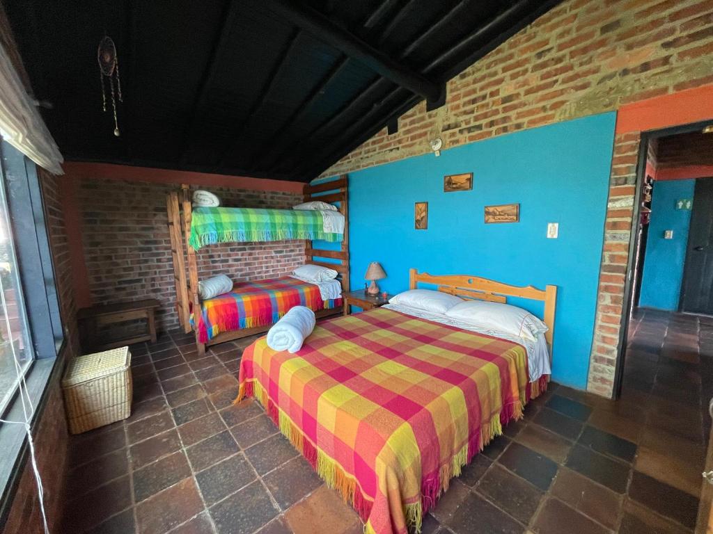 a bedroom with two beds and a brick wall at Refugio Explora Verde in Choachí