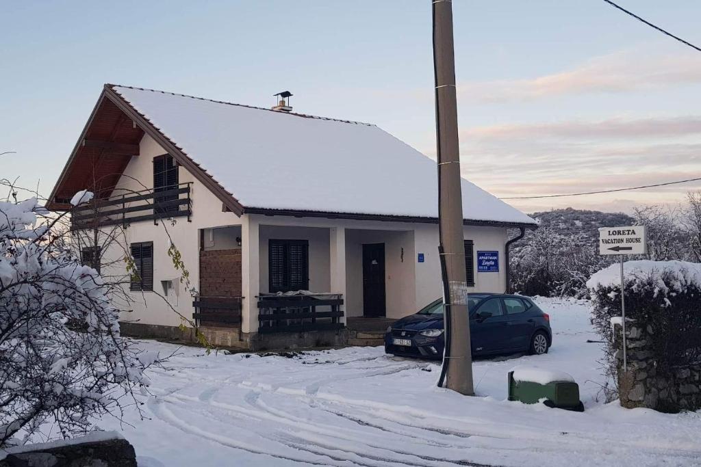 une petite maison avec une voiture garée dans la neige dans l'établissement Apartments with a parking space Lovinac, Velebit - 21748, à Lovinac