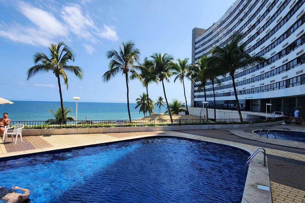 a swimming pool with palm trees and a building at @ondinaapartreservas Pé na Areia 441 in Salvador