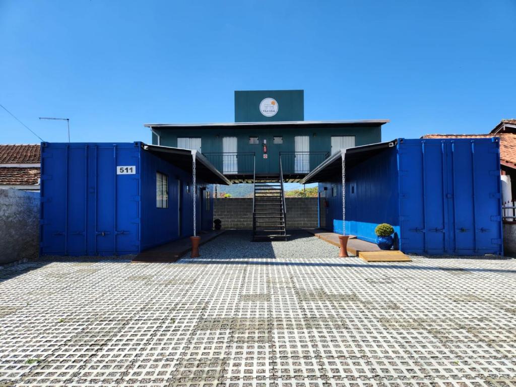 Un edificio con contenedores azules en un estacionamiento. en Vila Leal Hospedaria, en Penha