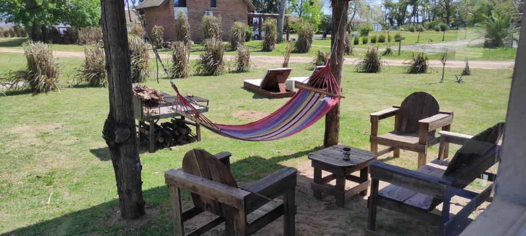 a hammock in a park with chairs and a table at Retiro San Francisco 2 hasta 6 huespedes -Pais Uruguay in Paysandú
