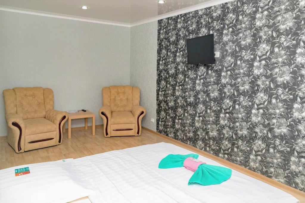 1 dormitorio con 2 sillas, 1 cama y TV en Хельсенки, en Petropavlovsk