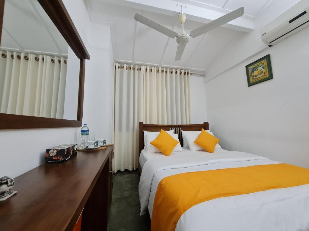 a bedroom with a bed with yellow pillows and a mirror at Hello Kandy Homestay in Kandy