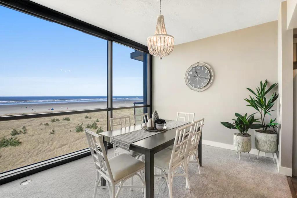 a dining room with a table and chairs and a view of the beach at Sand & Sea by DC in Seaside