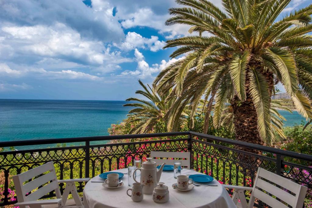 a table on a balcony with a view of the ocean at Douka Sea Front Residencies in Monemvasia