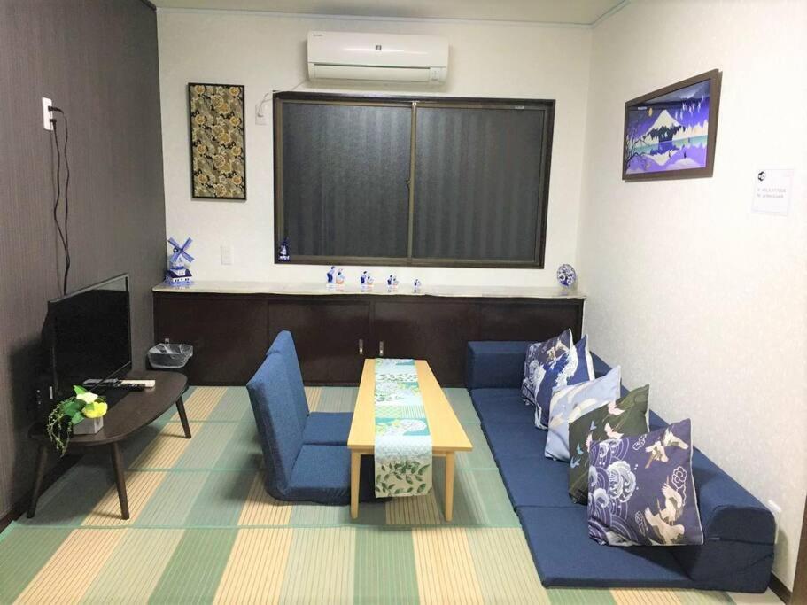 uma sala de estar com um sofá azul e uma mesa em Fortune House*JR 鶴橋なんばまで5分*観光便利*一軒家 最大6人 em Osaka