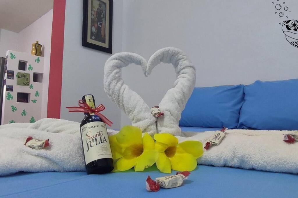 a bottle of wine on a bed with towels and flowers at Tortuga House in Puerto Baquerizo Moreno